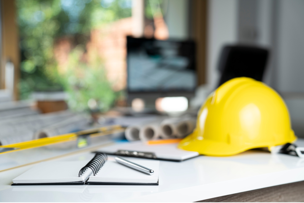 a yellow hard hat and pen on a white table