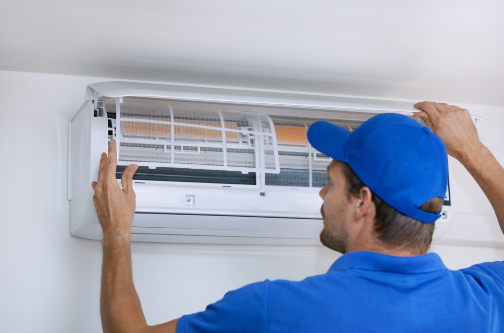 a man in a blue shirt and blue cap fixing a air conditioner